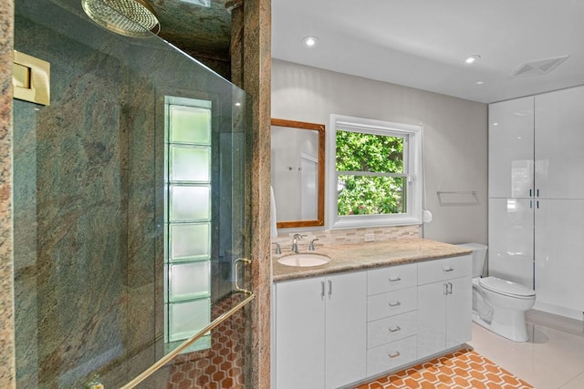 bathroom featuring toilet, vanity, backsplash, tile patterned floors, and a shower with door