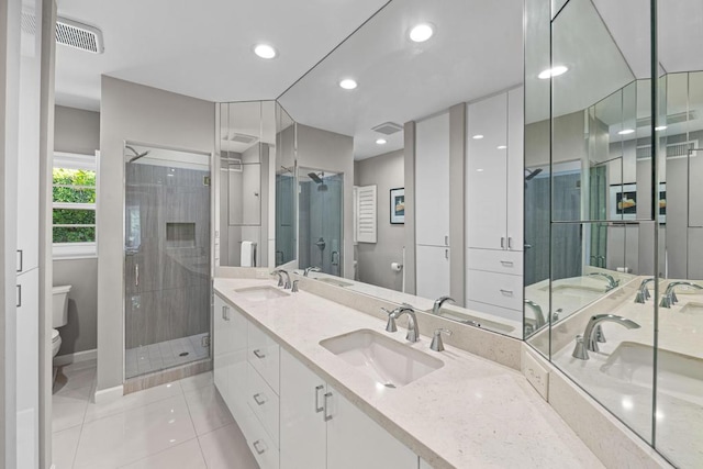 bathroom featuring toilet, tile patterned flooring, a shower with shower door, and vanity