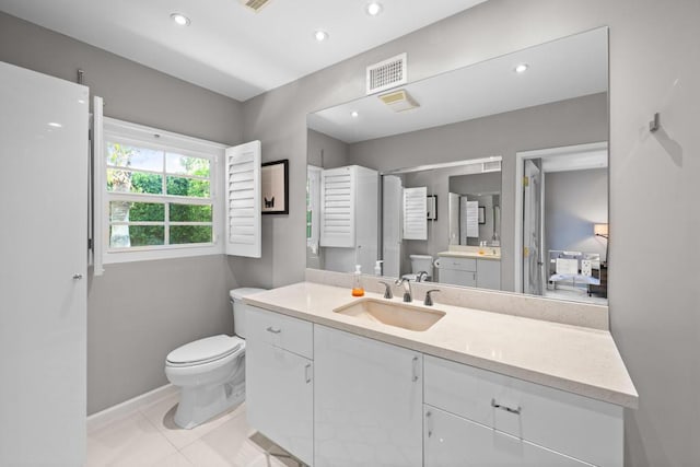 bathroom with toilet, vanity, and tile patterned flooring