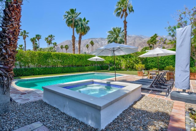 view of swimming pool featuring an in ground hot tub, a patio area, and a mountain view