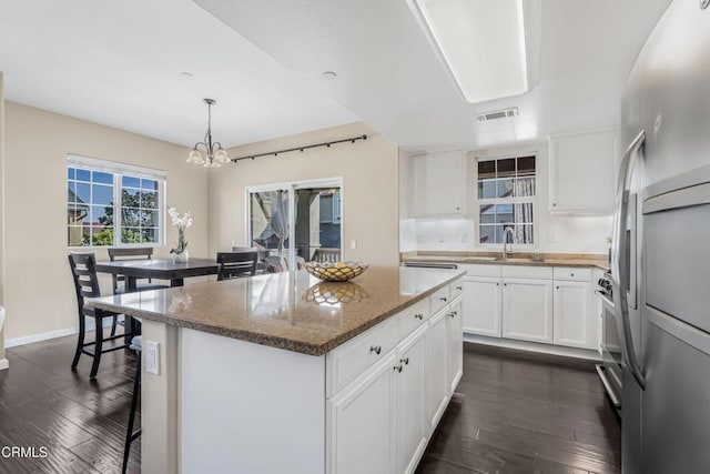 kitchen with white cabinets, hanging light fixtures, a center island, and stainless steel fridge