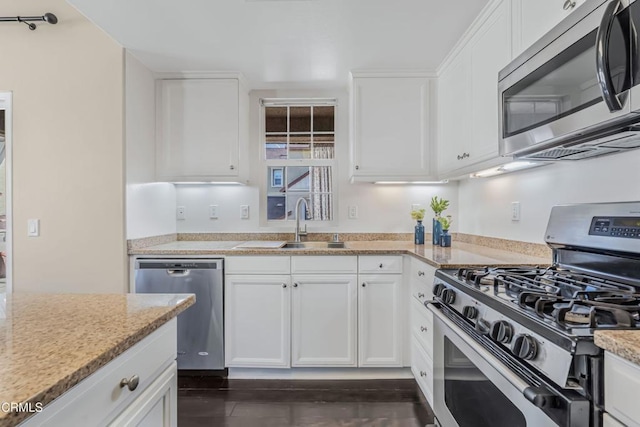 kitchen with stainless steel appliances, light stone countertops, and white cabinets