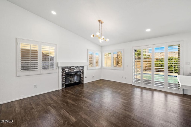 unfurnished living room featuring dark hardwood / wood-style flooring, lofted ceiling, a fireplace, and a notable chandelier