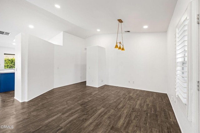 spare room featuring dark hardwood / wood-style floors, lofted ceiling, and a chandelier