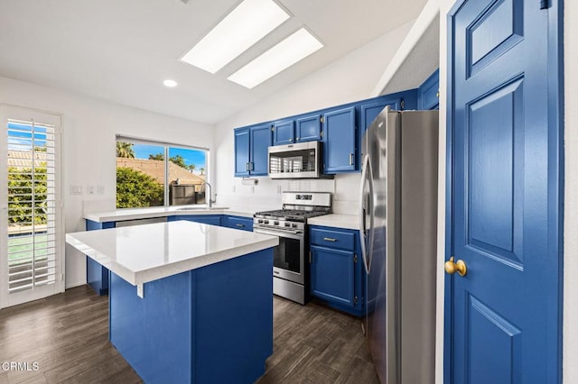 kitchen with blue cabinetry, sink, stainless steel appliances, and a kitchen island