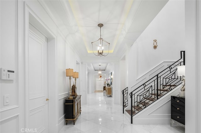 foyer featuring crown molding, a tray ceiling, and a chandelier