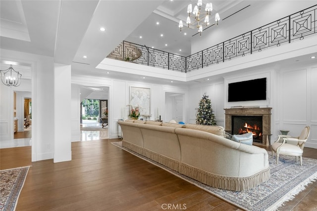 living room featuring an inviting chandelier, a premium fireplace, a high ceiling, and hardwood / wood-style flooring