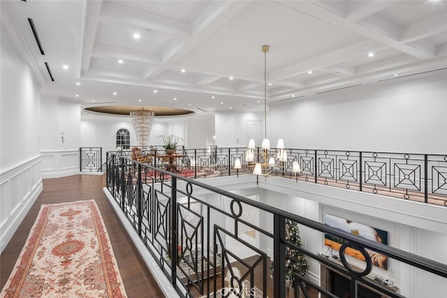 hall featuring dark wood-type flooring, an inviting chandelier, coffered ceiling, and beamed ceiling