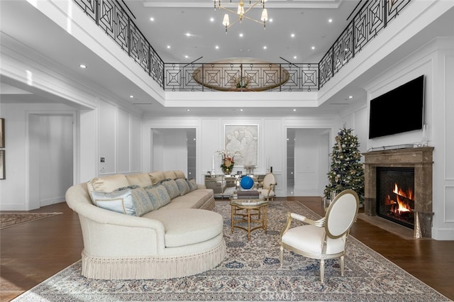 living room featuring a fireplace, dark hardwood / wood-style flooring, a towering ceiling, and an inviting chandelier