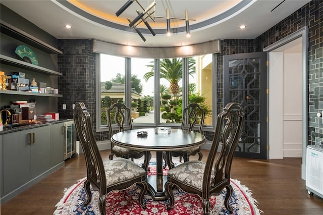 dining room with dark wood-type flooring, an inviting chandelier, and a tray ceiling