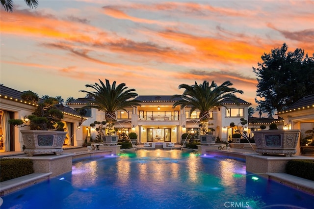 pool at dusk featuring pool water feature