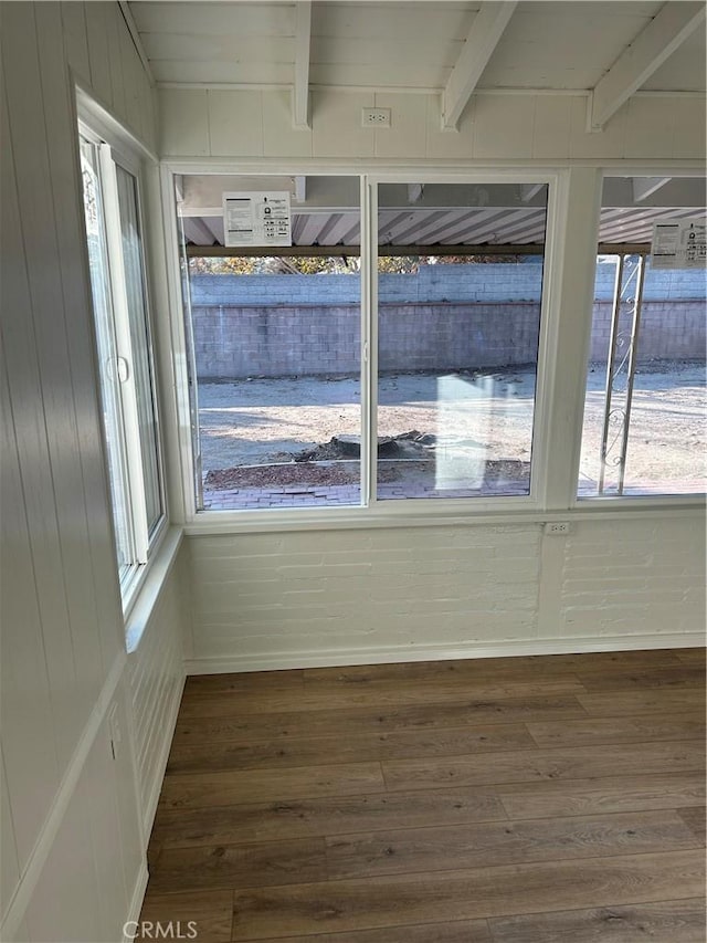 unfurnished room with dark wood-type flooring and beam ceiling