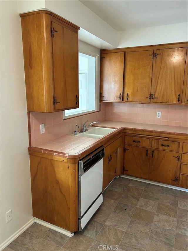 kitchen featuring sink, backsplash, dishwasher, and tile countertops