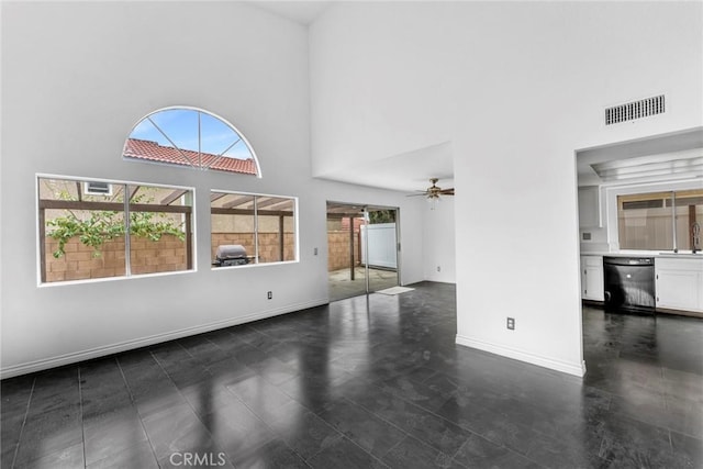 unfurnished living room with ceiling fan, a high ceiling, and sink