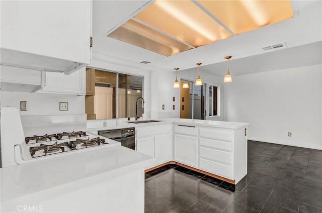 kitchen with white cabinetry, kitchen peninsula, dishwasher, pendant lighting, and sink