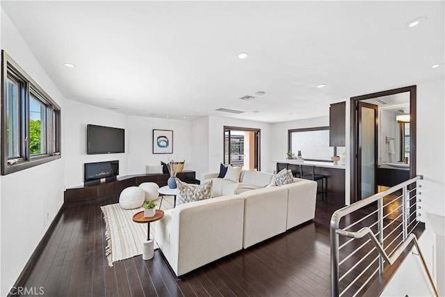 living room with dark wood-type flooring and a wealth of natural light