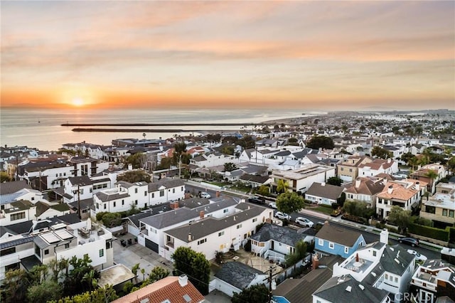 aerial view at dusk featuring a water view