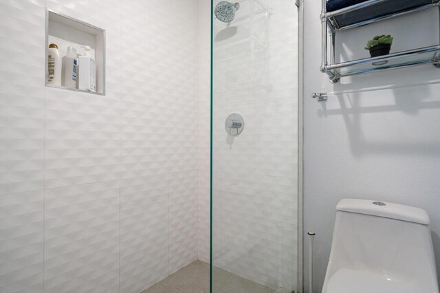 bathroom with toilet and a tile shower