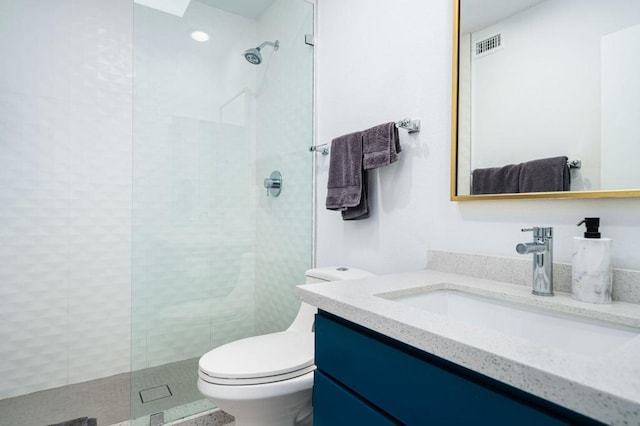 bathroom featuring toilet, vanity, and tiled shower