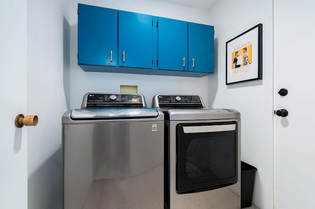 clothes washing area with cabinets and washer and clothes dryer