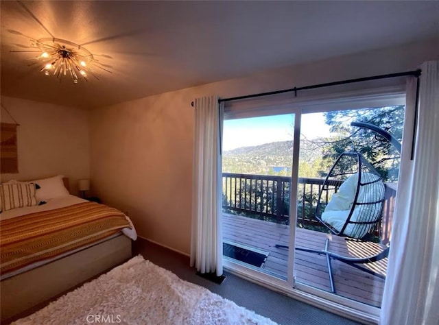 carpeted bedroom with a mountain view, access to outside, and an inviting chandelier