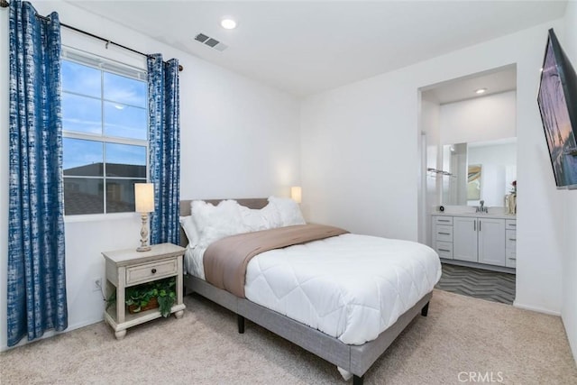 bedroom with sink, ensuite bath, and light carpet