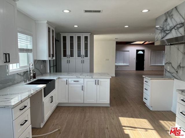 kitchen with decorative backsplash, sink, light stone counters, and white cabinets