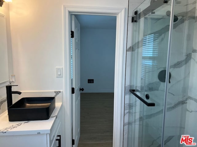 bathroom with wood-type flooring, walk in shower, and vanity