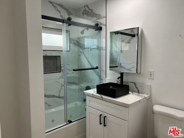 full bathroom with combined bath / shower with glass door, vanity, and toilet