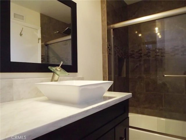 bathroom featuring combined bath / shower with glass door and vanity