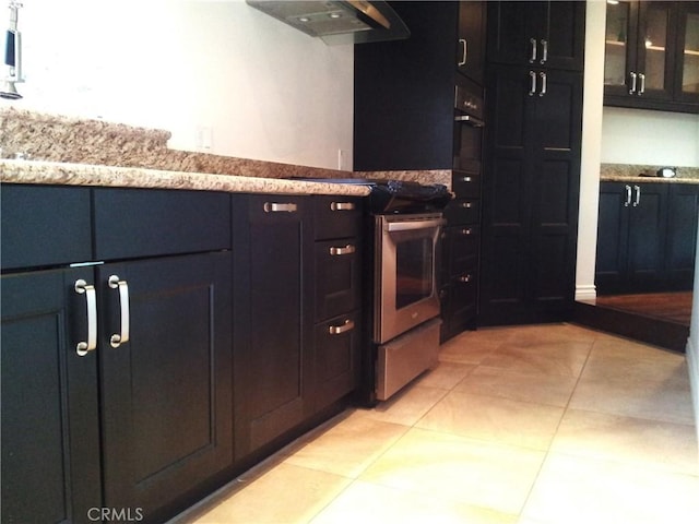 kitchen with stainless steel electric range oven, exhaust hood, light tile patterned floors, and black oven