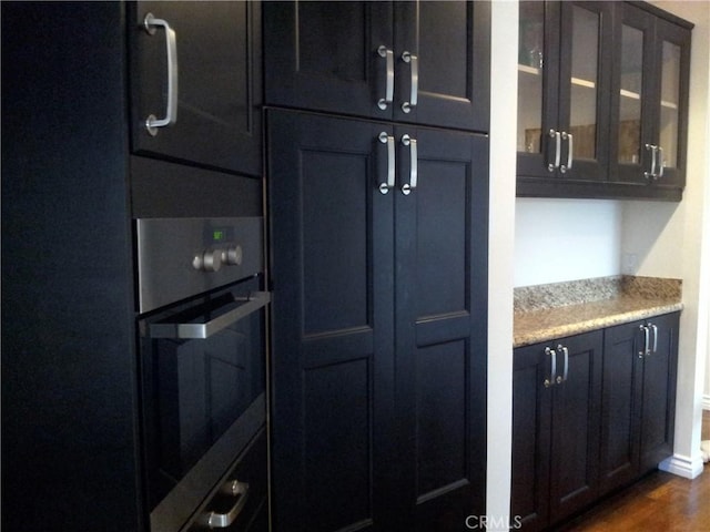 kitchen with light stone countertops, dark hardwood / wood-style floors, and oven