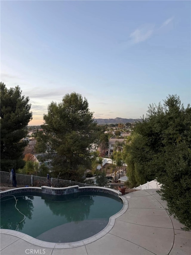 pool at dusk with a patio area