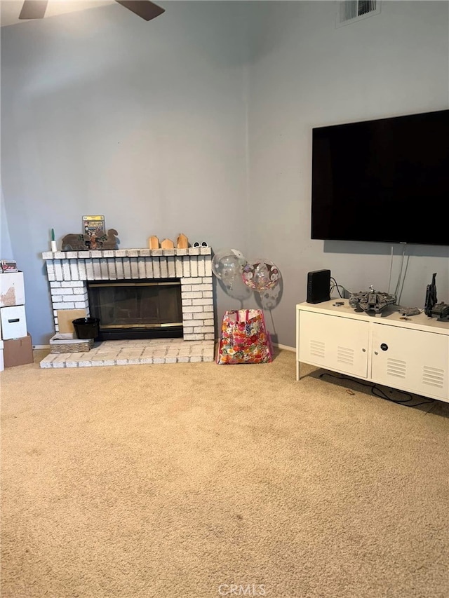 carpeted living room with a brick fireplace and ceiling fan