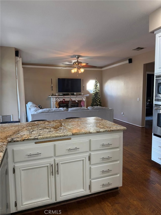 kitchen featuring dark hardwood / wood-style floors, light stone counters, white cabinetry, and stainless steel appliances