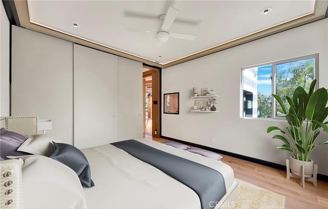 bedroom featuring ceiling fan, a closet, and light hardwood / wood-style flooring