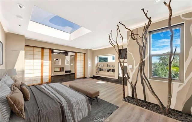 bedroom featuring a skylight, crown molding, and hardwood / wood-style flooring