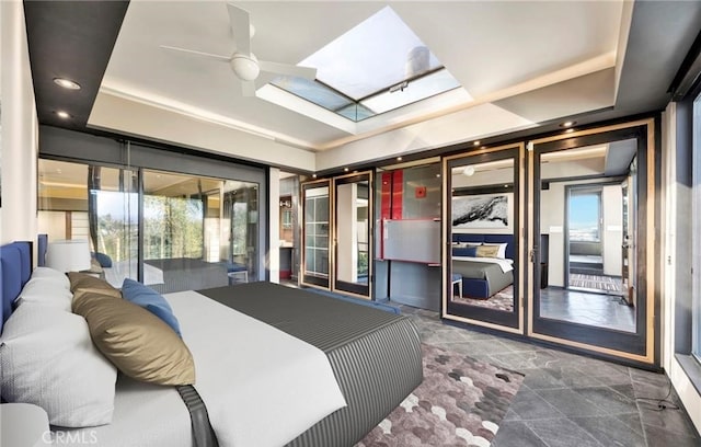 bedroom with a skylight, a raised ceiling, access to outside, and multiple windows