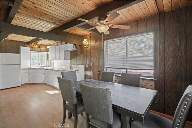 dining space with a wealth of natural light, light hardwood / wood-style flooring, and beamed ceiling