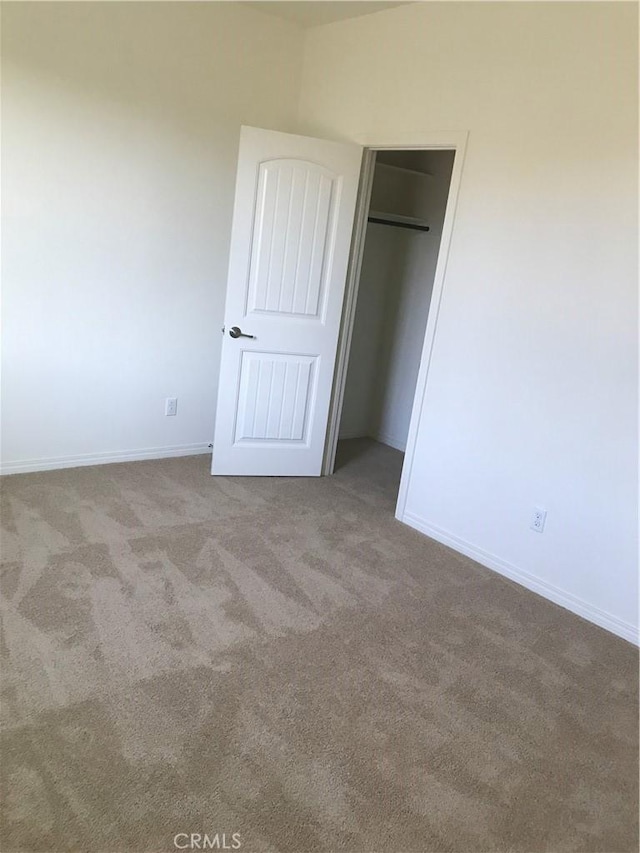 unfurnished bedroom featuring light carpet and a closet