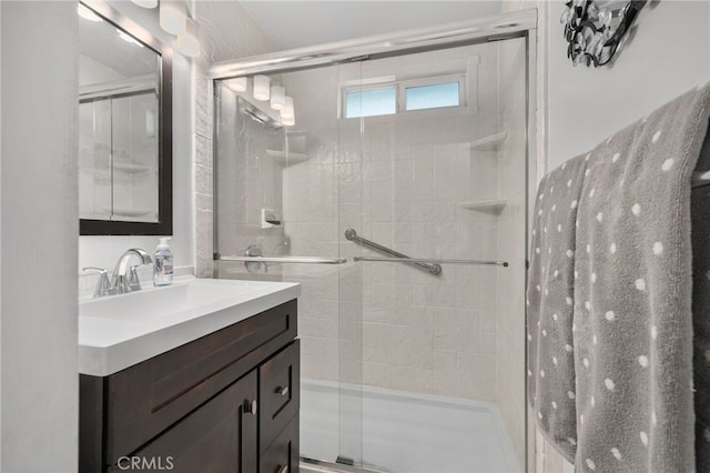 bathroom featuring a shower with shower door and vanity