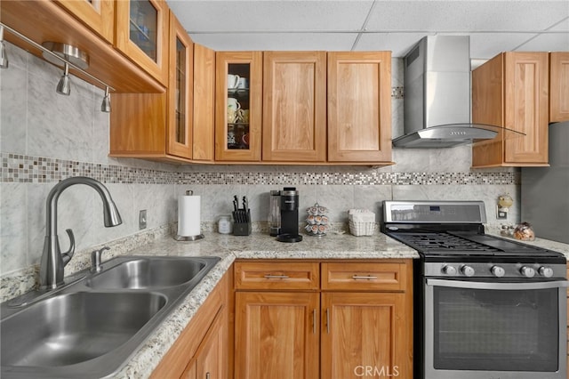 kitchen with backsplash, stainless steel gas stove, sink, and wall chimney exhaust hood