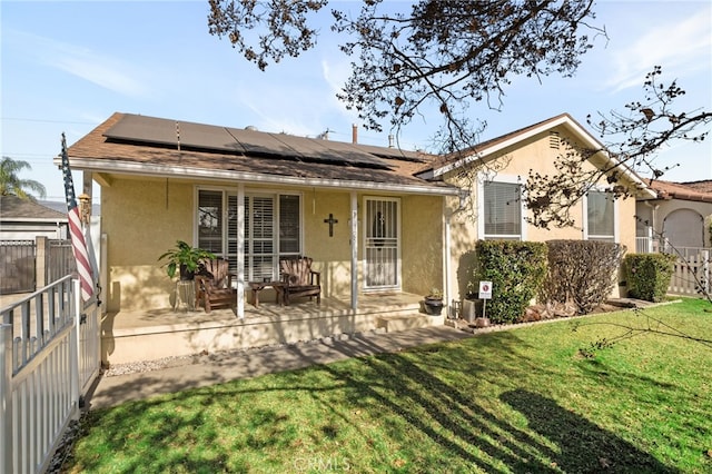 back of property featuring a yard and solar panels