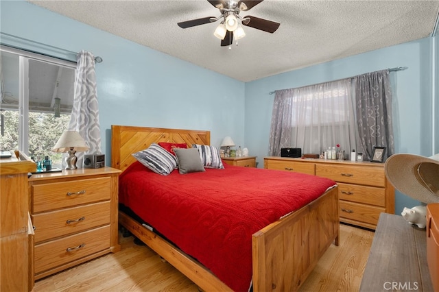 bedroom with ceiling fan, light hardwood / wood-style floors, and a textured ceiling