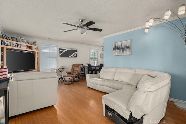 living room with a textured ceiling, ceiling fan, ornamental molding, and hardwood / wood-style flooring