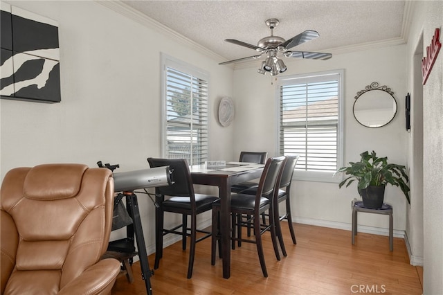 dining area featuring ceiling fan, wood-type flooring, a textured ceiling, and ornamental molding