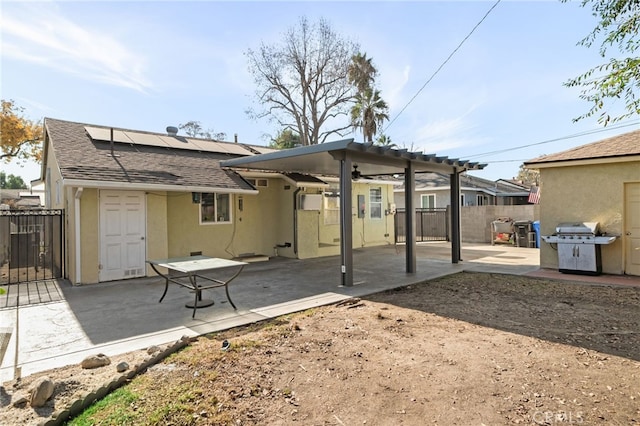 rear view of property with ceiling fan, solar panels, and a patio