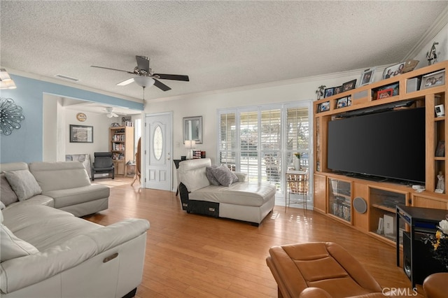 living room with ceiling fan, light wood-type flooring, crown molding, and a textured ceiling