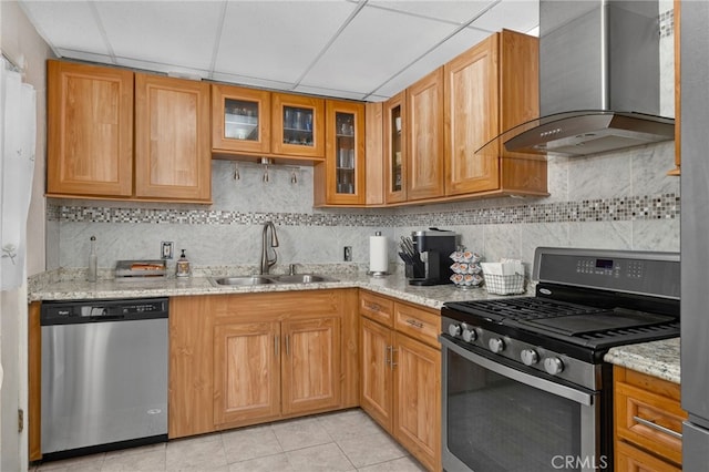 kitchen featuring light stone countertops, a paneled ceiling, wall chimney exhaust hood, stainless steel appliances, and sink