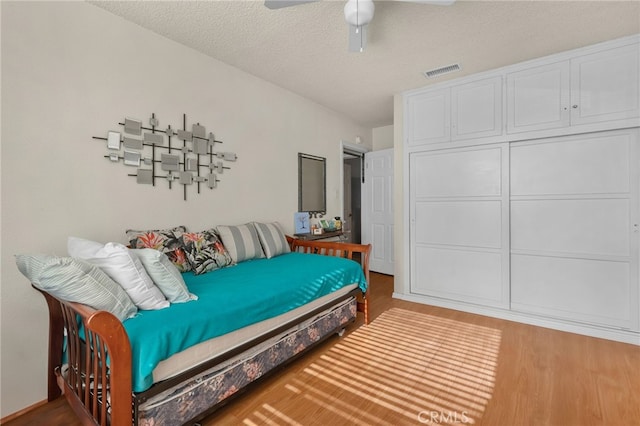 bedroom with ceiling fan, a textured ceiling, and hardwood / wood-style floors